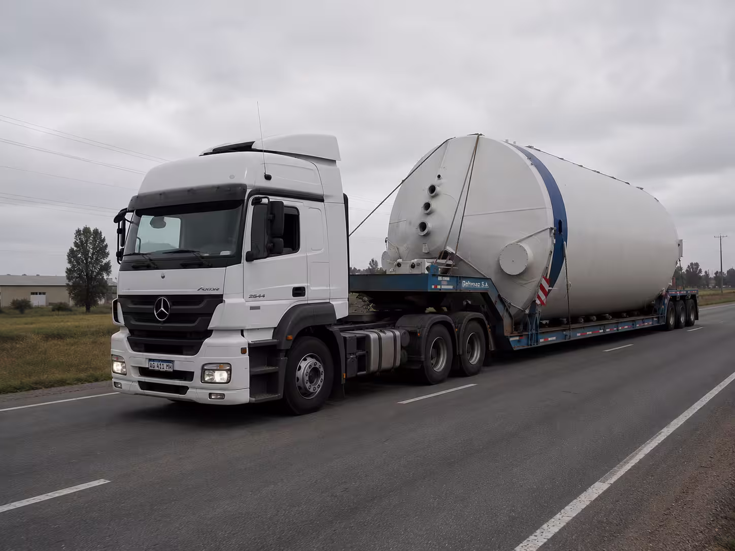 Carreta prancha da Rutas del Sur transportando um tanque industrial fora de medida na estrada